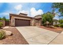 A well-maintained home featuring a wide driveway, desert landscaping, and stone veneer accents on the pillars at 18719 E Pelican Ct, Queen Creek, AZ 85142