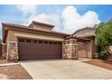 Home exterior with stone accents on garage and entry pillars with a large driveway and well-kept yard at 18719 E Pelican Ct, Queen Creek, AZ 85142