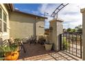 Covered patio area featuring outdoor seating, potted plants, and a wrought iron gate at 19667 N 260Th N Ln, Buckeye, AZ 85396