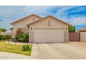 View of the home's facade, a two car garage, and a well maintained lawn with a light blue sky overhead at 20977 N 84Th Ln, Peoria, AZ 85382