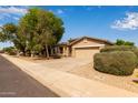 Well-maintained single story home with a two car garage and mature shrubs at 2590 S Buckaroo Trl, Gilbert, AZ 85295