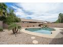 Lush backyard featuring a private pool with rock accents and mature landscaping at 2834 E Devon Ct, Gilbert, AZ 85296