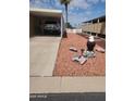 A front yard with desert landscaping, a carport, and decorative yard sculptures at 9302 E Broadway Rd # 157, Mesa, AZ 85208
