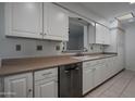 Bright kitchen features white cabinets, neutral countertops, and stainless steel dishwasher at 10325 W Prairie Hills Cir, Sun City, AZ 85351