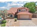 Charming home featuring a red tile roof, a two-car garage, and desert landscaping in the front yard at 1813 E Sheena Dr, Phoenix, AZ 85022