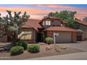 Charming home with a red tile roof, a two-car garage, and desert landscaping in the front yard under a sunset at 1813 E Sheena Dr, Phoenix, AZ 85022