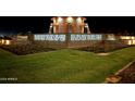 Illuminated community entrance with water features, lush landscaping, and prominent signage at night at 23036 E Oriole Way, Queen Creek, AZ 85142