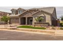 Charming two-story home with a stone facade, well-manicured lawn, and three-car garage at 23036 E Oriole Way, Queen Creek, AZ 85142