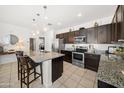 Modern kitchen featuring granite countertops, stainless steel appliances, and dark wood cabinets at 23690 W Ripple Rd, Buckeye, AZ 85326