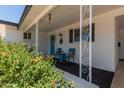Inviting front porch with decorative white pillars, cozy seating, and a vibrant turquoise door, creating a welcoming entrance at 701 N 55Th Pl, Mesa, AZ 85205