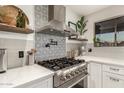 Modern kitchen features stainless steel appliances, a patterned backsplash, and sleek countertops at 12866 W Orange Dr, Litchfield Park, AZ 85340