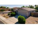Well-maintained home with desert landscaping, mature shrubs, and a paved driveway leading to the garage at 13170 W Clarendon Ave, Litchfield Park, AZ 85340