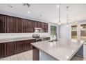 Bright kitchen featuring dark cabinets, stainless steel appliances, tile backsplash, and a large island with a sink at 15551 W Poinsettia Dr, Surprise, AZ 85379