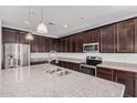 Modern kitchen featuring dark cabinets, stainless steel appliances, granite countertops, and a large island with a sink at 15551 W Poinsettia Dr, Surprise, AZ 85379