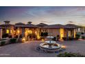Impressive home exterior showcasing a fountain, lush landscaping, and a paver driveway at twilight at 4328 N Pinnacle Ridge Cir, Mesa, AZ 85207