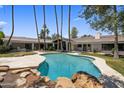 Beautiful backyard oasis with a freeform pool, lush landscaping, and a covered patio at 4801 E Horseshoe Rd, Paradise Valley, AZ 85253