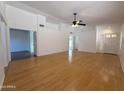 Bright living room featuring hardwood floors, neutral walls, ceiling fan, and entryways to other rooms at 1020 W Sunward Dr, Gilbert, AZ 85233