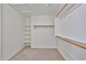 Walk-in closet with wood rods, shelving, and neutral carpet flooring at 11626 W Holly St, Avondale, AZ 85392