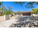 A single-story home with desert landscaping, a paved driveway, and a two-car brown garage door at 28 E Winged Foot Rd, Phoenix, AZ 85022