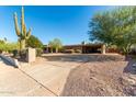 Southwestern-style home boasting desert landscaping, an attached carport, and a prominent saguaro cactus at 12423 N 64Th St, Scottsdale, AZ 85254