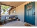 Inviting front porch featuring a bench, potted plants, a welcome mat, and an attractive blue front door at 12423 N 64Th St, Scottsdale, AZ 85254