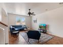 Bright living room featuring a comfortable blue sofa, ceiling fan, and large window that fills the room with natural light at 18222 W Lundberg St, Surprise, AZ 85388