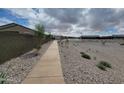 A long sidewalk is surrounded by rocks and very little plant life as it winds through the community at 19390 N Fiano Dr, Maricopa, AZ 85138