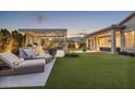 Beautifully designed backyard with a covered patio, built-in grill, comfortable lounge seating, and lush green lawn at 20797 W Rattler Rd, Buckeye, AZ 85396