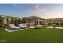 Serene backyard features an outdoor kitchen, sun loungers and lovely green artificial grass at 20797 W Rattler Rd, Buckeye, AZ 85396