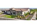 Well-maintained home featuring a tile roof, stone accents, lush lawn, manicured shrubbery, and an attached garage at 20797 W Rattler Rd, Buckeye, AZ 85396
