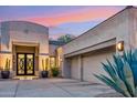 Front entry of a home, highlighting a well-lit entryway with a concrete driveway and desert landscaping at 21240 N 74Th Pl, Scottsdale, AZ 85255