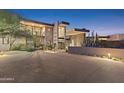 Elegant home featuring desert landscaping, a stone accent wall, and a grand entrance with ample lighting at 39602 N Charles Blair Macdonald Rd, Scottsdale, AZ 85262