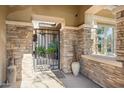 Covered front entryway featuring stone accents, a gated entry, and decorative planters, creating a welcoming ambiance at 5291 S Bradshaw Pl, Chandler, AZ 85249