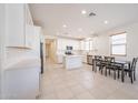 This well-lit kitchen has white cabinets, an island, and a dining table at 7648 W Kerby Ave, Phoenix, AZ 85043