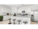 The kitchen features white cabinets, a stainless steel microwave and a refrigerator, and seating at the breakfast bar at 10614 W Bloch Rd, Tolleson, AZ 85353