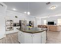 Open concept kitchen with stainless steel appliances, large island, white cabinets, and tile flooring, flowing into the living room at 1442 W Laurel Ave, Gilbert, AZ 85233