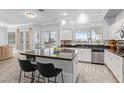 Bright kitchen featuring an island with bar seating, stainless steel appliances, tile flooring, and natural light from the windows at 1442 W Laurel Ave, Gilbert, AZ 85233