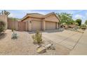 Tan home featuring a long driveway, three car garage and sparse desert landscaping in the front yard at 16219 S 14Th Way, Phoenix, AZ 85048