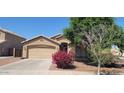 Inviting single-story home with a two-car garage and a tidy front yard featuring a lovely, flowering bush at 2202 S 82Nd Ave, Phoenix, AZ 85043