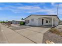 Charming single-story home features a white exterior, low maintenance landscaping, and covered carport at 2241 N Nicklaus Dr, Mesa, AZ 85215