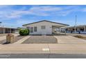 Charming single-story home features a white exterior, low maintenance landscaping, and covered carport at 2241 N Nicklaus Dr, Mesa, AZ 85215