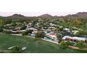 Scenic aerial view of a luxury home, golf course and mountain views at 23002 N Country Club Trl, Scottsdale, AZ 85255
