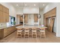 Bright kitchen features an oversized center island, barstool seating, and light wood cabinets at 23002 N Country Club Trl, Scottsdale, AZ 85255
