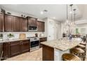 Modern kitchen featuring stainless steel appliances, dark wood cabinets, and a granite countertop island with barstool seating at 26391 N 107Th Dr, Peoria, AZ 85383