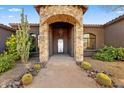 Elegant stone archway entrance features decorative wrought iron door and desert landscaping at 28025 N 156Th Pl, Scottsdale, AZ 85262