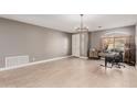 Bright, open-concept living room with tile floors and a modern light fixture at 43615 W Roth Rd, Maricopa, AZ 85138