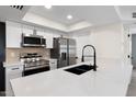Contemporary kitchen featuring stainless steel appliances, white cabinets, a quartz countertop island, and a black sink with faucet at 520 N Stapley Dr # 166, Mesa, AZ 85203