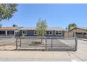 Inviting single-story home with a well-maintained gray exterior, gravel landscaping, and gated front yard at 7135 W Flower St, Phoenix, AZ 85033