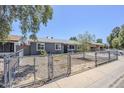 Cozy single-story home boasting a gray exterior, low-maintenance front yard, and secure chain-link fence at 7135 W Flower St, Phoenix, AZ 85033