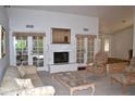 Bright living room boasts a fireplace, French doors, neutral color palette and carpet at 9130 W Utopia Rd, Peoria, AZ 85382